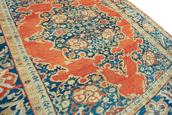 Rust orange rug with a traditional, complex deep blue and cream floral medallion design.