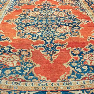 Traditional high-contrast rug showing an orange field with elaborate blue and gold floral patterns.