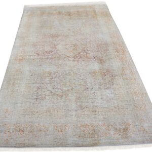 Pale gray rug with short fringe and a subtle, faded traditional pattern in rust and purple.