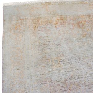 Distressed low pile rug close-up showing light grey, faded orange patterns, and short white fringe.