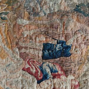 Aged, low-pile tapestry detail in muted tan, beige, red, and strong blue abstract patterns with a striped border.