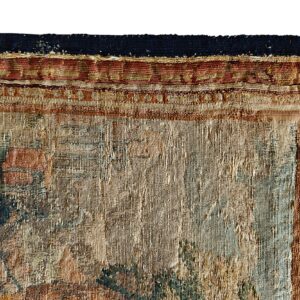 Detail of a textured low-pile rug featuring intricate patterns in beige, brown, rust red, and faded teal.