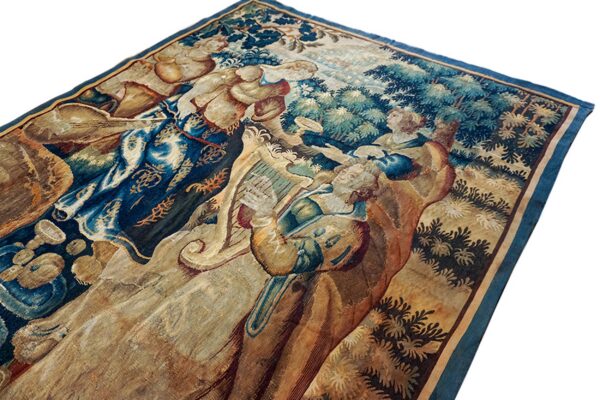 Detailed tapestry rug featuring robed figures and trees in rich blue, green, and faded gold colors.