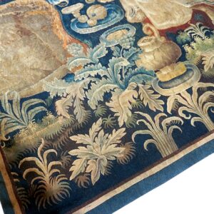Worn flatweave rug section with a detailed blue, beige, and green acanthus leaf pattern and striped border.