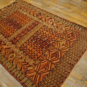 Geometric patterned rug in shades of terracotta, navy, and gold sits on distressed wide plank wood floor.
