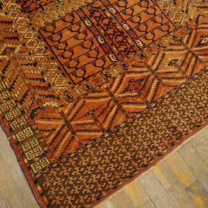 Rust and navy geometric rug with intricate tribal patterns shown on light, worn wooden floorboards.