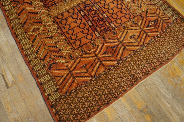 Rust and navy geometric rug with intricate tribal patterns shown on light, worn wooden floorboards.