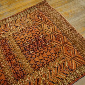 Orange and dark blue patterned tribal rug displayed on weathered light wooden flooring.