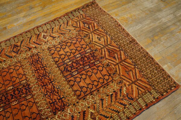 Orange and dark blue patterned tribal rug displayed on weathered light wooden flooring.