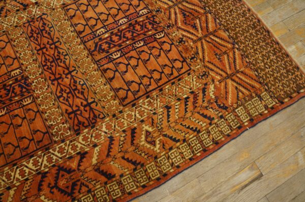 High-pile orange rug with contrasting dark blue geometric tribal designs on light wood planks.