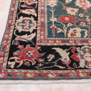 Traditional rug corner featuring teal, black, red, and beige floral patterns on pale wood flooring.