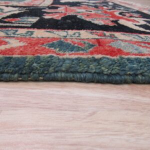 Close-up shows a thick pile rug with borders of teal, coral, cream, and black over light wooden flooring.