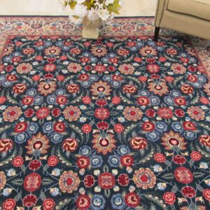 Plush dark blue rug with a dense red and multicolor floral pattern next to an upholstered armchair.