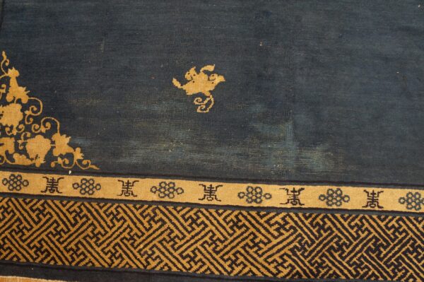 The dark blue rug field has gold floral elements and geometric fretwork borders.