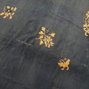Deep blue low-pile rug with scattered gold botanical and navy geometric motifs.