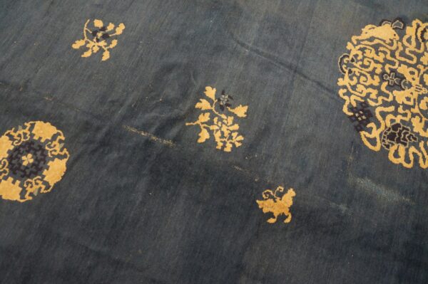 Deep blue low-pile rug with scattered gold botanical and navy geometric motifs.