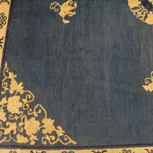 Deep indigo rug with a dense gold geometric border and scrolling floral corner designs.