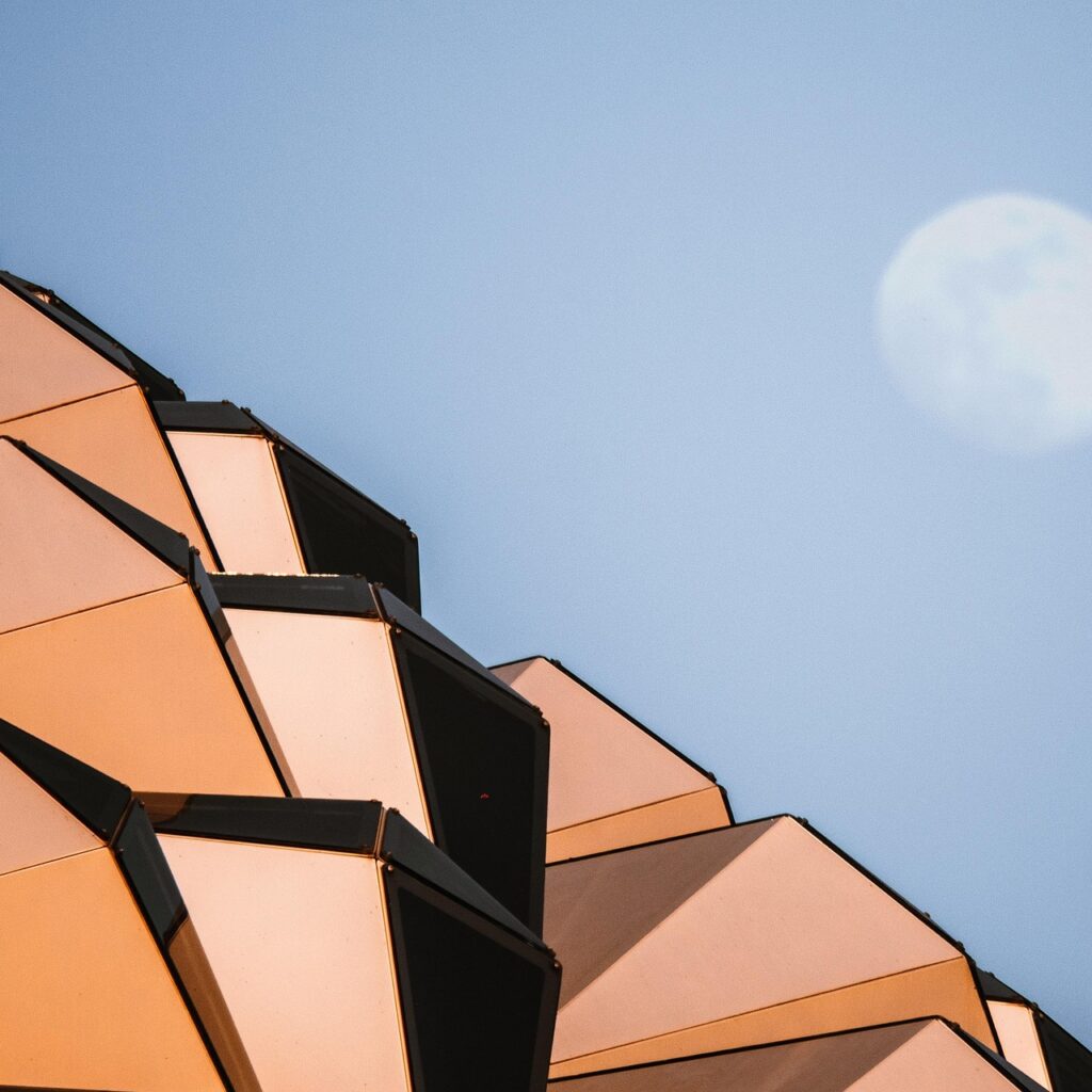 Geometric building with moon backdrop.
