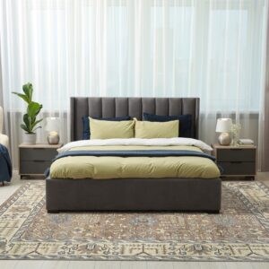 A muted traditional brown and beige rug defines a modern bedroom with light flooring and grey furniture.