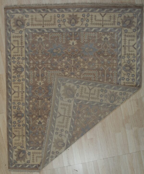 Brown and tan patterned rug with blue accents displayed on light wood flooring with a corner folded over.