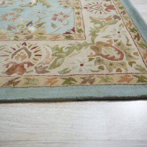 Textured pale blue rug featuring cream and earth-toned floral patterns rests on light wood flooring.