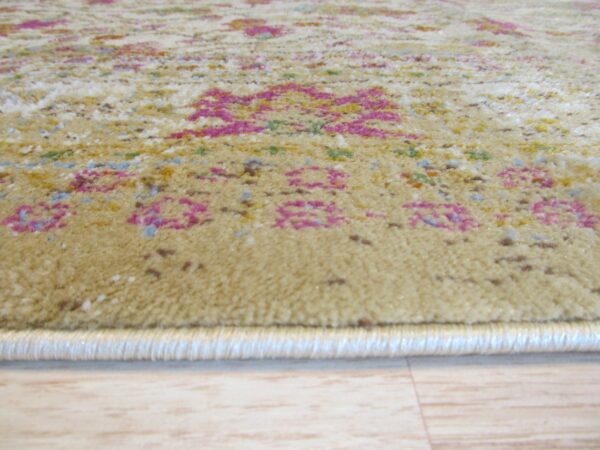 Textured beige rug with bright pink and multi-color patterns resting on light wood plank flooring.