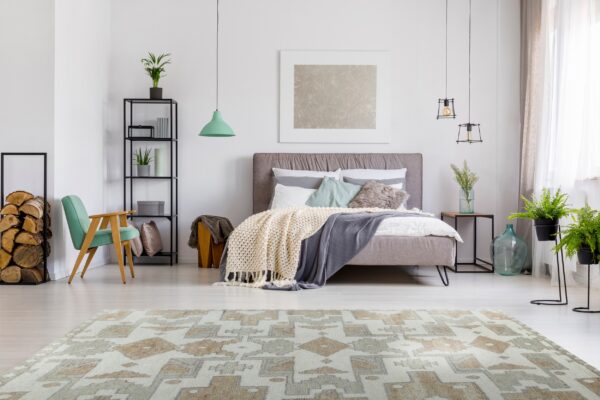 A low-pile beige and gray geometric rug anchors a bright, modern bedroom with light wood floors.