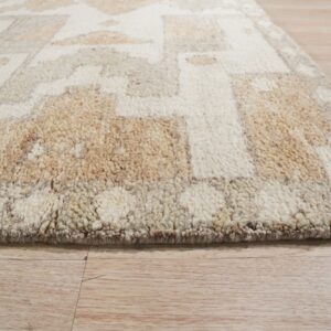 A close-up view of a shaggy cream and tan geometric rug on light plank flooring.
