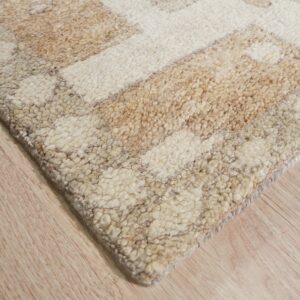 Textured, chunky pile rug with abstract cream and beige pattern lying on light hardwood.