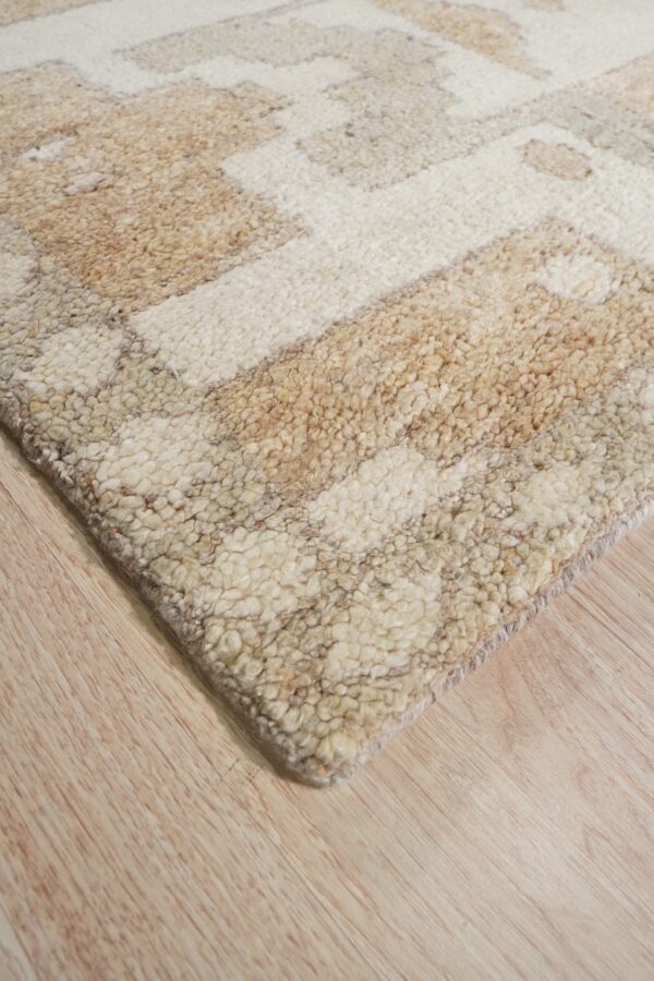 Textured, chunky pile rug with abstract cream and beige pattern lying on light hardwood.