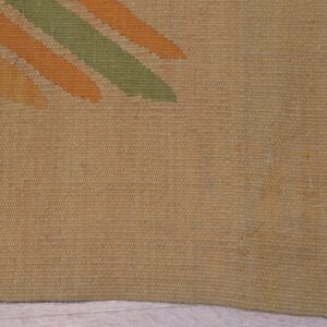 Golden yellow flatweave rug with diagonal orange and olive stripes rests on light wooden planks.