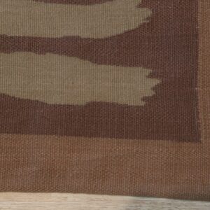 Flat-weave rug detail showing abstract brown and tan organic shapes and a solid border on wood flooring.