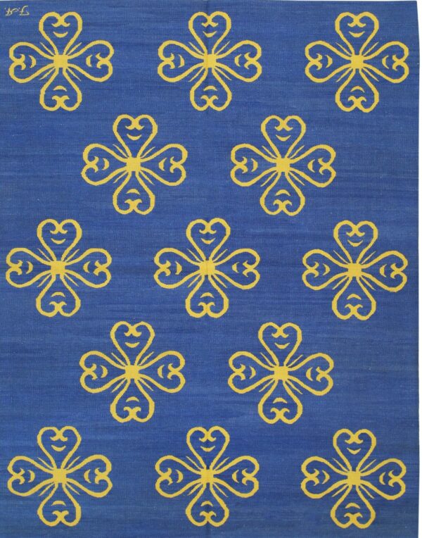 Blue flatweave rug displaying repeating yellow stylized four-leaf clover patterns across the surface.