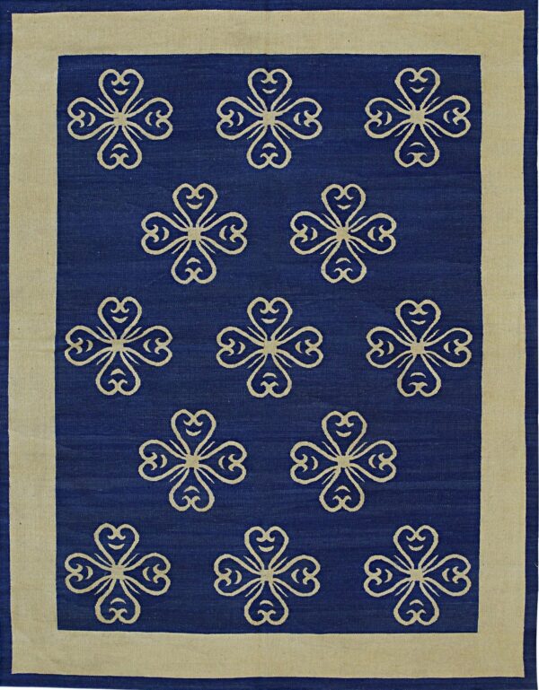 A blue rug features repeating beige four-leaf clover motifs centered within a wide, solid beige border.