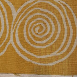 A flatwoven rug in gold and cream featuring large concentric spiral patterns.