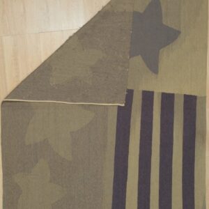 Khaki and deep gray flatweave rug with abstract stars and stripes is folded on light wood flooring.