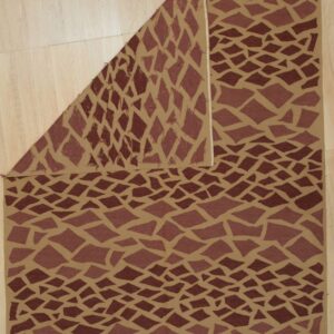Tan flatwoven rug with dark brown abstract diamond shapes, displayed folded on light wood flooring.