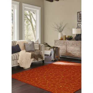 Orange and gold abstract rug on dark hardwood flooring in a living room with large windows.
