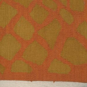 Orange and gold flatweave rug showing a geometric pattern detail on light wood flooring.