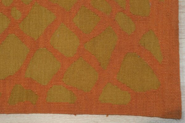 Orange and gold flatweave rug showing a geometric pattern detail on light wood flooring.