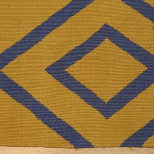 Low pile rug with yellow and blue geometric diamond pattern resting on light wood flooring.