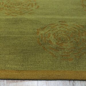 Olive green flatweave rug featuring abstract rusty orange circular designs resting on light wood flooring.