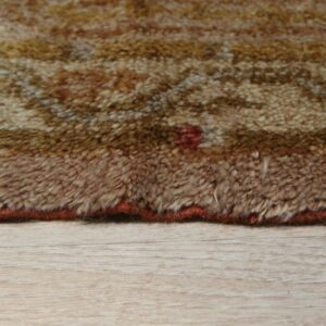 High pile brown and gold rug edge showing a mottled pattern over light wood flooring.