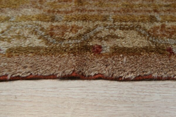 High pile brown and gold rug edge showing a mottled pattern over light wood flooring.