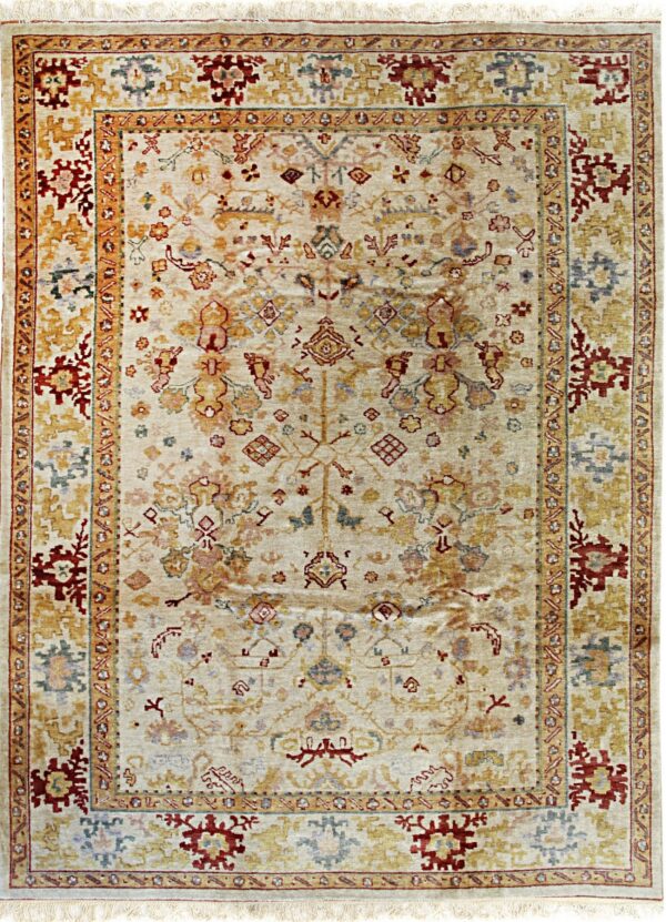 Rectangular area rug with an ivory field and distressed traditional motifs in gold, rust red, and slate blue.