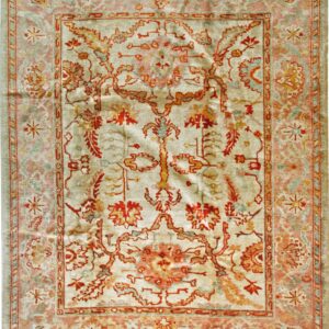 A rectangular rug featuring an intricate red, gold, and pink floral pattern on a pale green background.