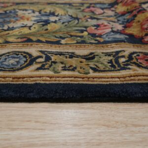 The plush edge of a navy, beige, and multicolor floral rug rests on light wood planks.