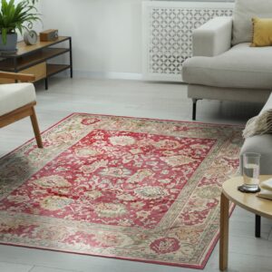 A distressed red and beige traditional rug grounds a neutral living room with light wooden floors and cream furniture.
