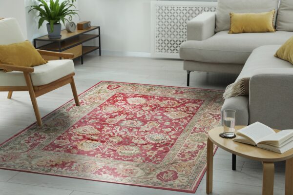 A distressed red and beige traditional rug grounds a neutral living room with light wooden floors and cream furniture.