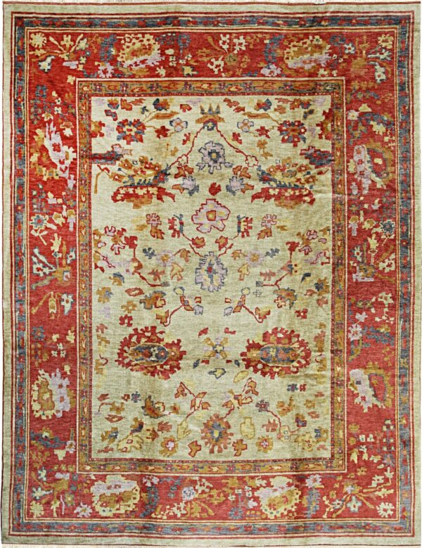 A traditional rug featuring a pale olive field and a wide patterned border of rust red.